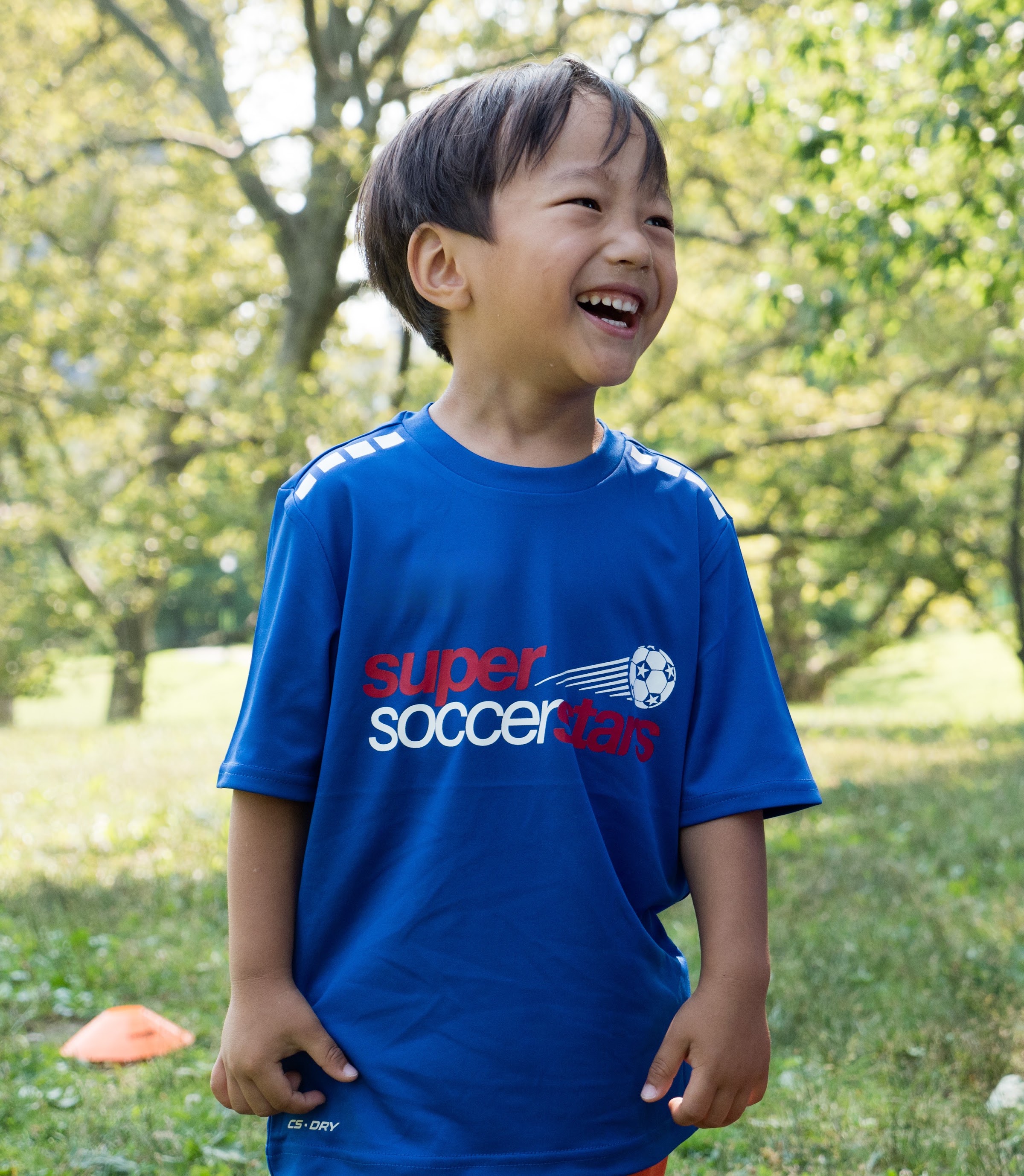 A smiling Soccer Stars player stands on a sunny field