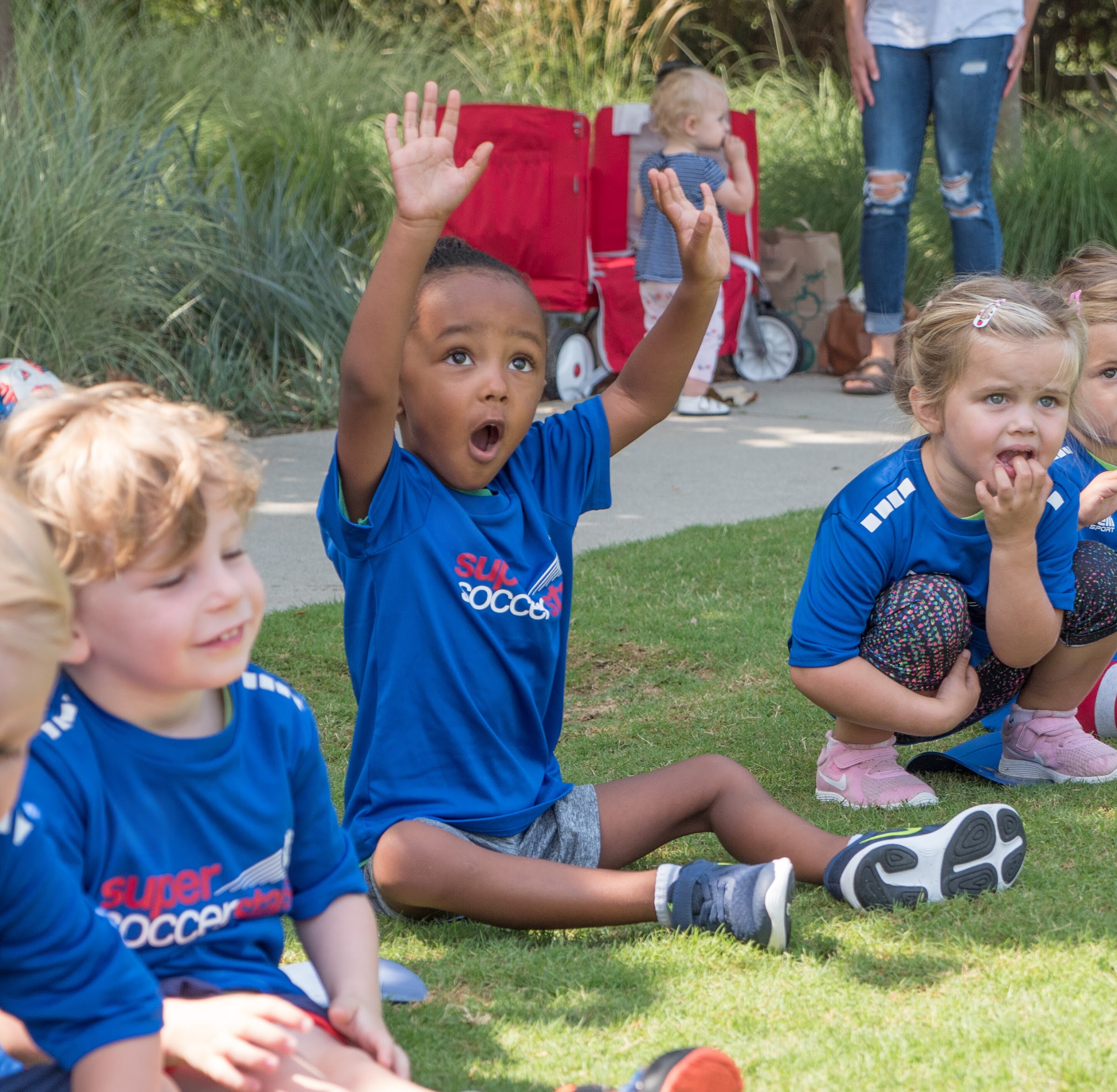 Young players gather with a coach during an outdoor camp